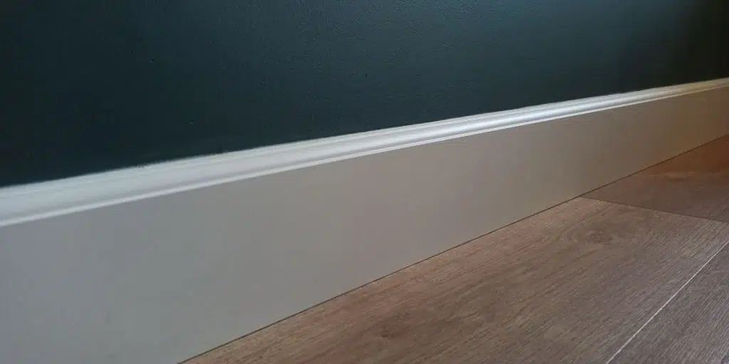 Plinthe blanche sur un mur vert foncé